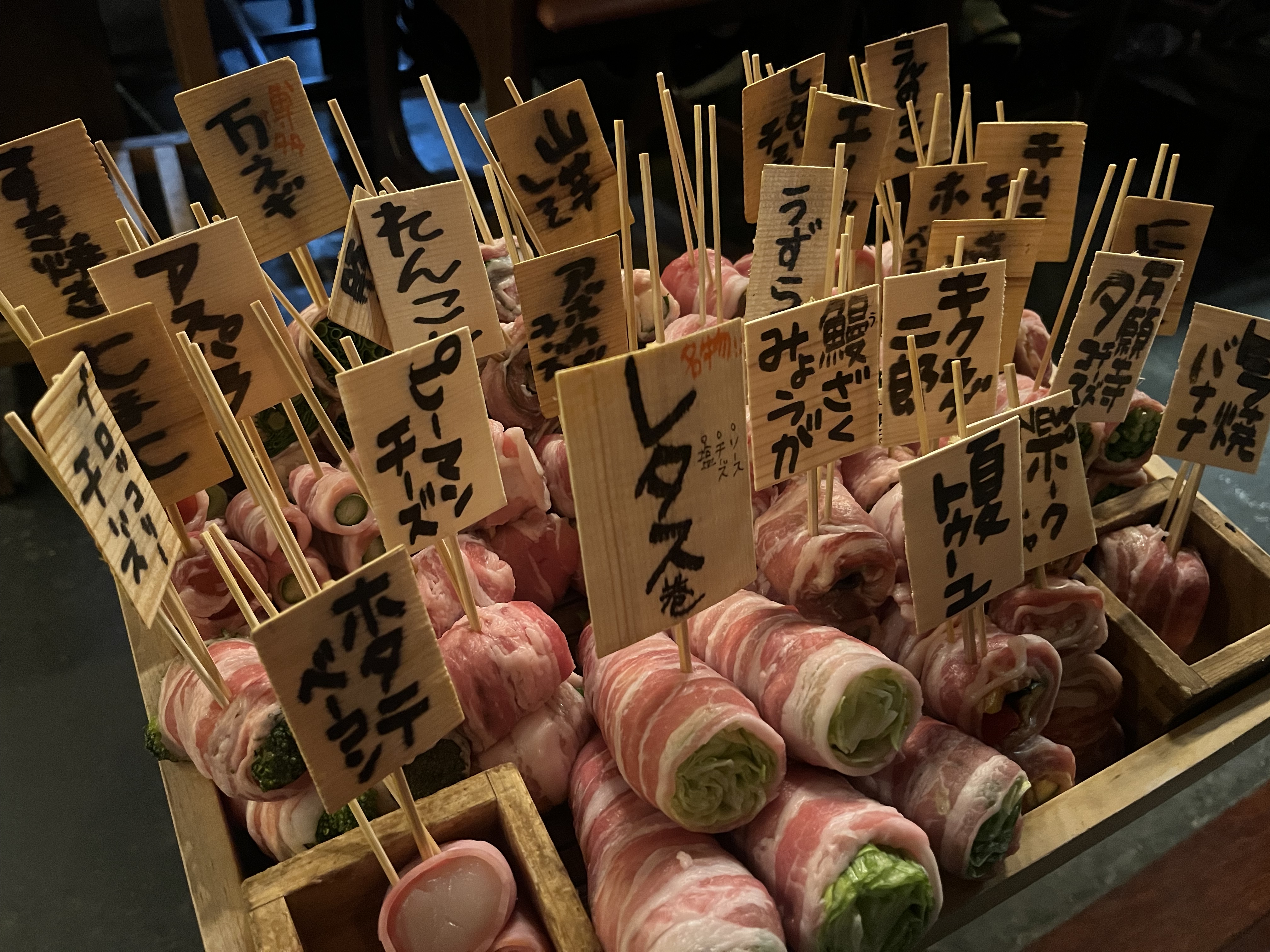 肉巻き野菜串がたくさん木箱に入って並べられている画像